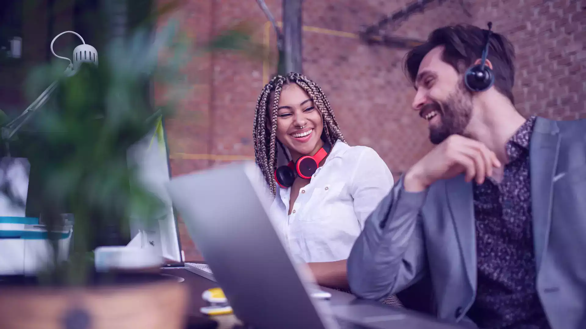 Two colleagues sit in front of a laptop, discussing the improved results from using explainer videos in their marketing strategy.