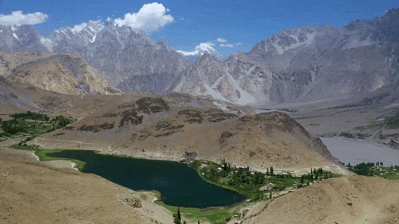 Large wide shot capturing a vast mountain landscape with a green lake and small village below, demonstrating how a wide camera angle establishes scale, setting, and context in cinematic storytelling hosted on Cinema8.